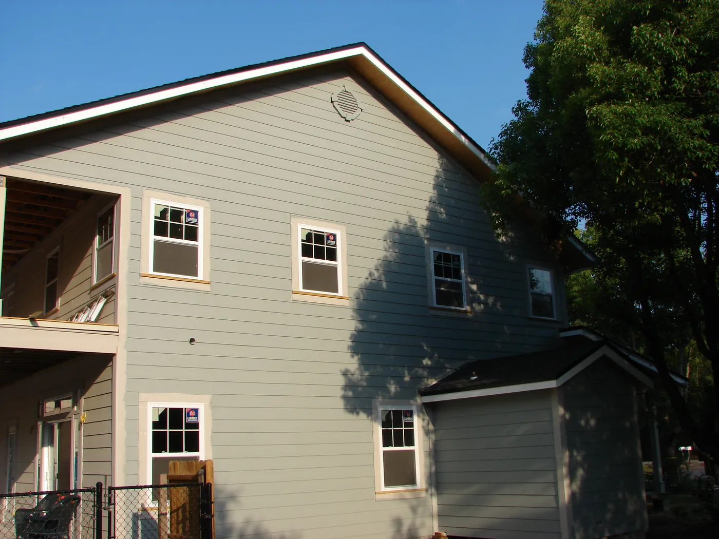 Completed tan and gray two-story home exterior with lap siding and white-trimmed windows