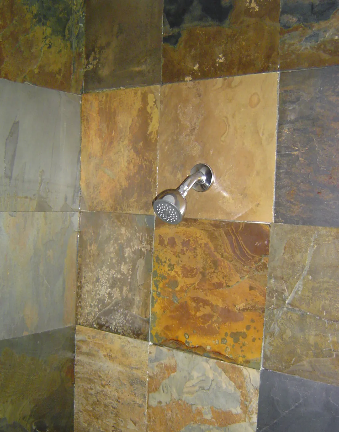 Walk-in shower with natural multicolor slate tile walls and chrome showerhead