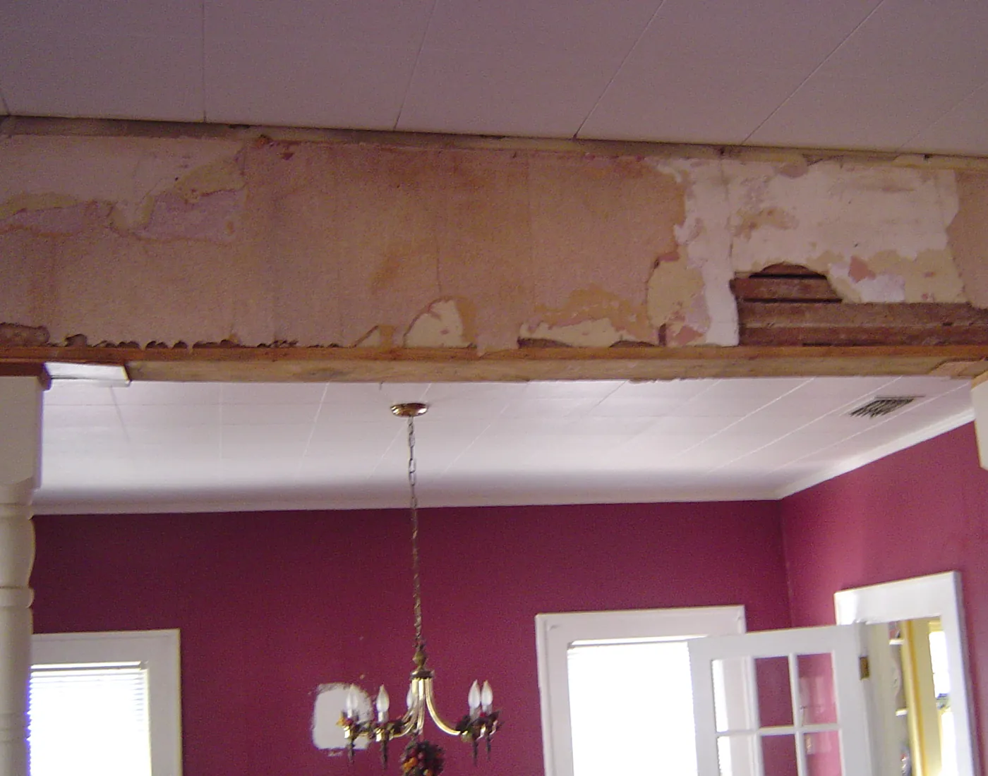 Finished dining room painted deep magenta with a chandelier and white French doors