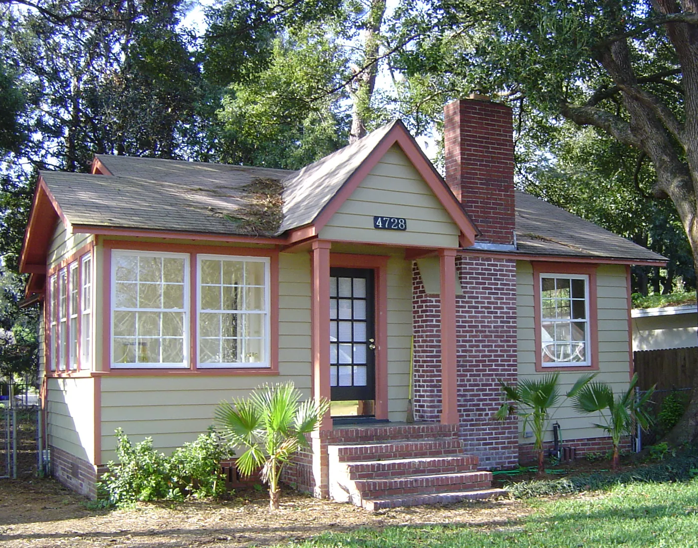 Restored brick-and-siding bungalow exterior with fresh landscaping and mature shade trees