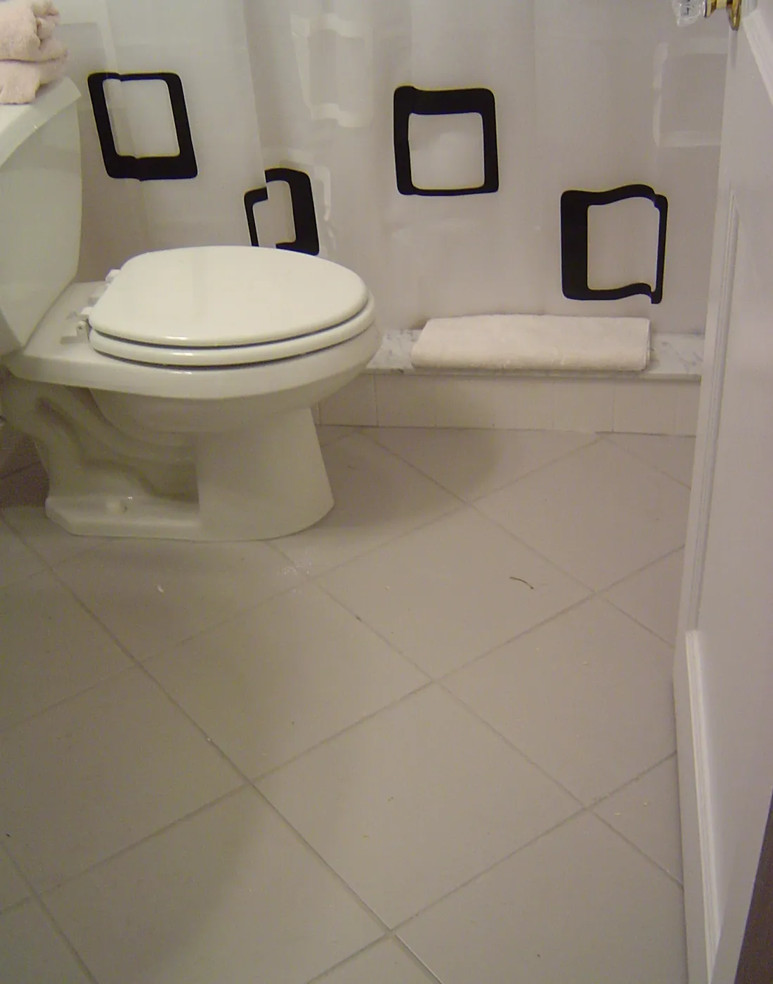 Finished bathroom with tiled tub surround, white tile floor and new toilet