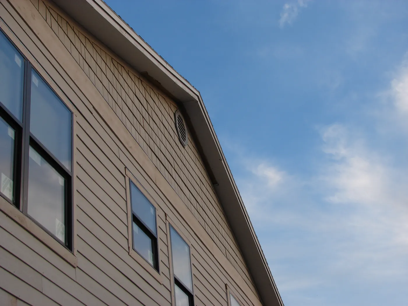 Corner of a home with newly installed horizontal siding under a bright blue sky