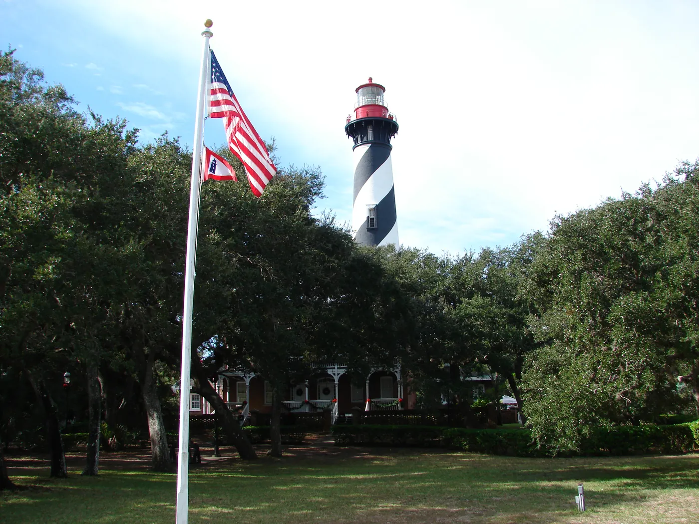 St. Augustine lighthouse with an American flag flying on the grounds, a landmark of St. Johns County