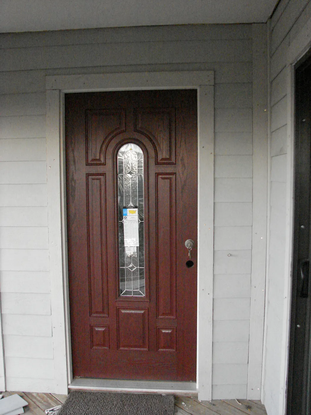 New mahogany front entry door with an arched decorative glass insert set in painted trim