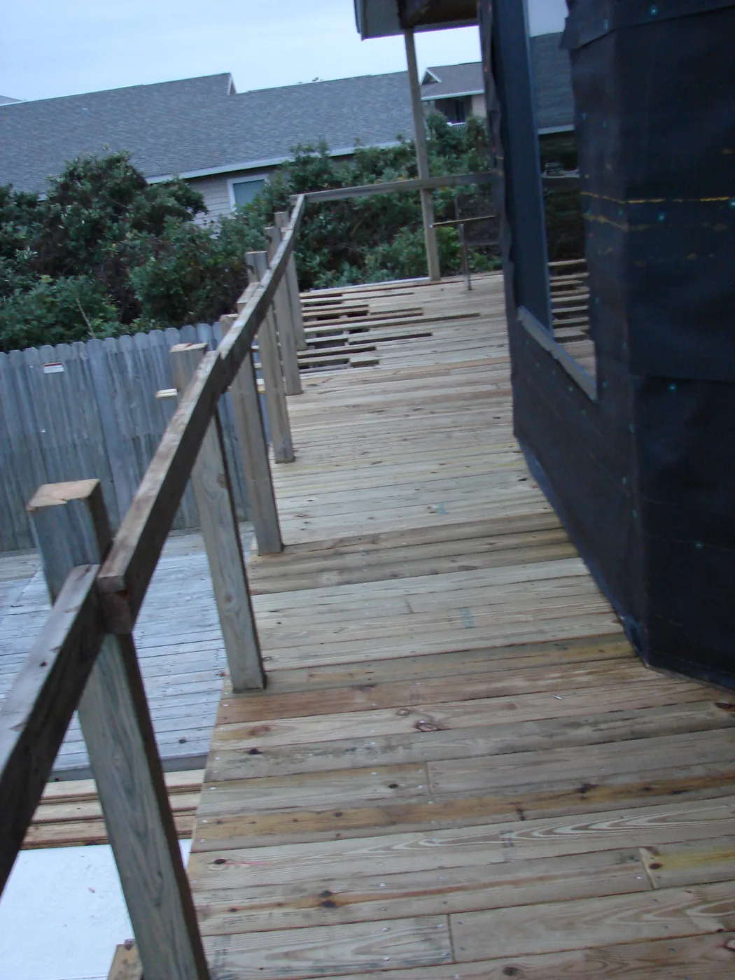 Rebuilt wood deck and sloped ramp walkway with railing on a coastal home