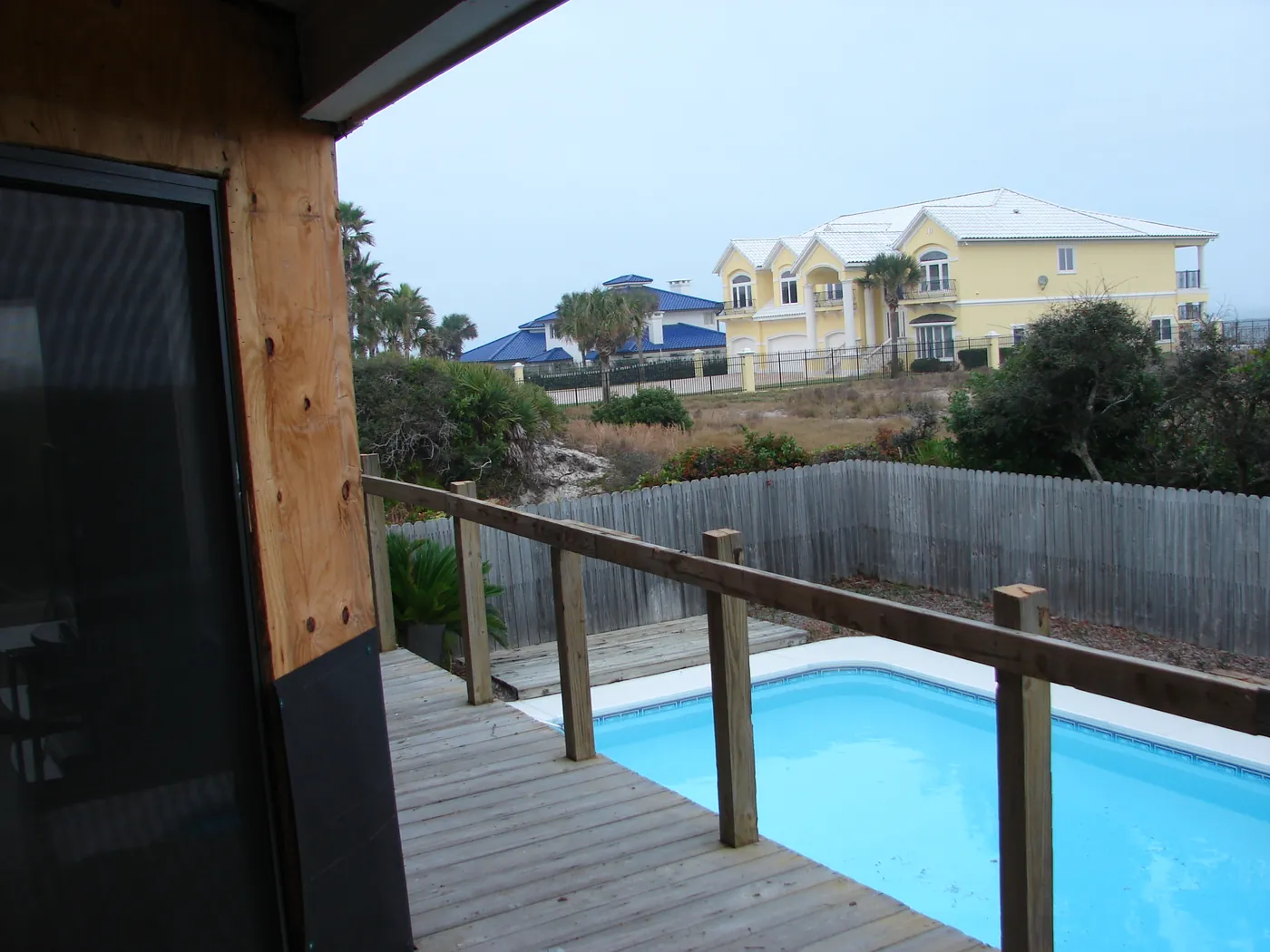 Backyard pool viewed from a screened deck with a new glass-panel railing
