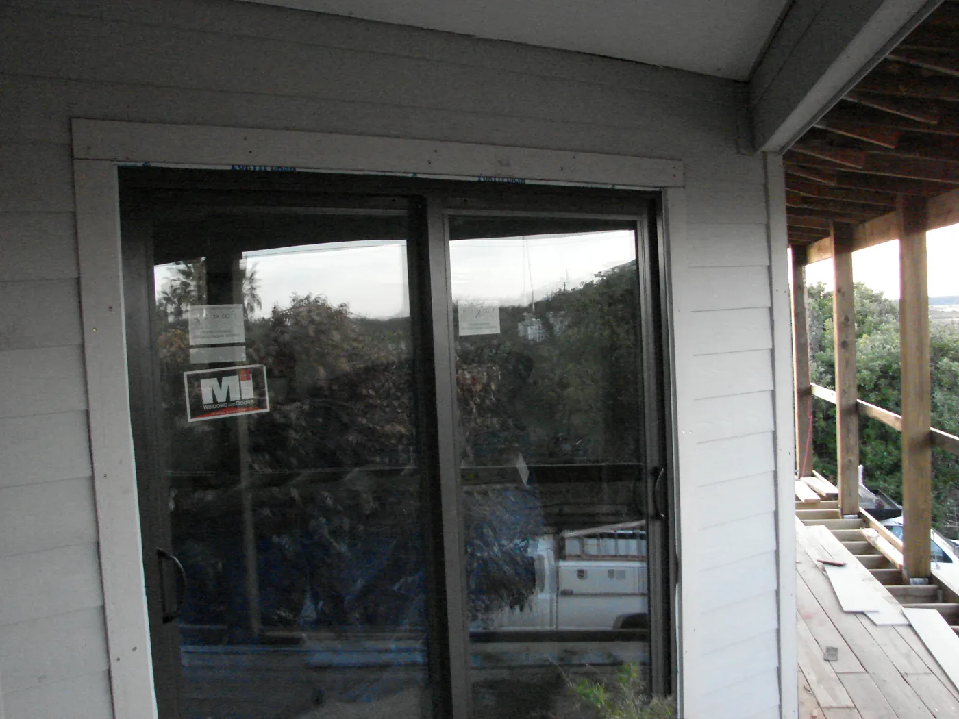 Renovated exterior wall with a large sliding glass patio door and new siding