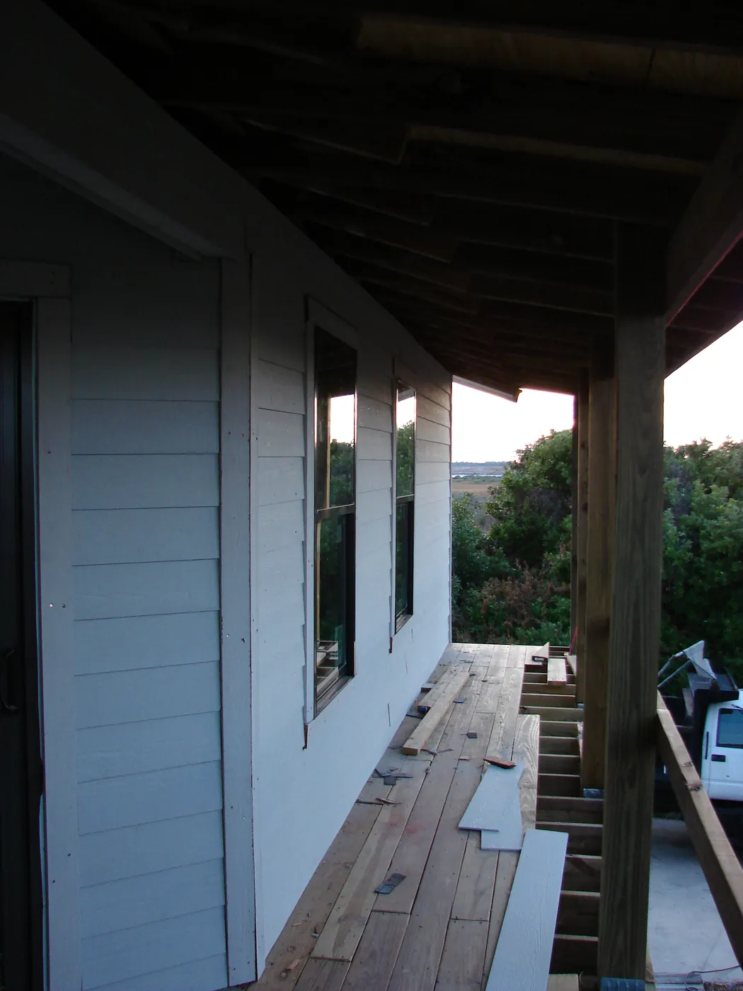 Covered porch with new white lap siding and freshly installed windows