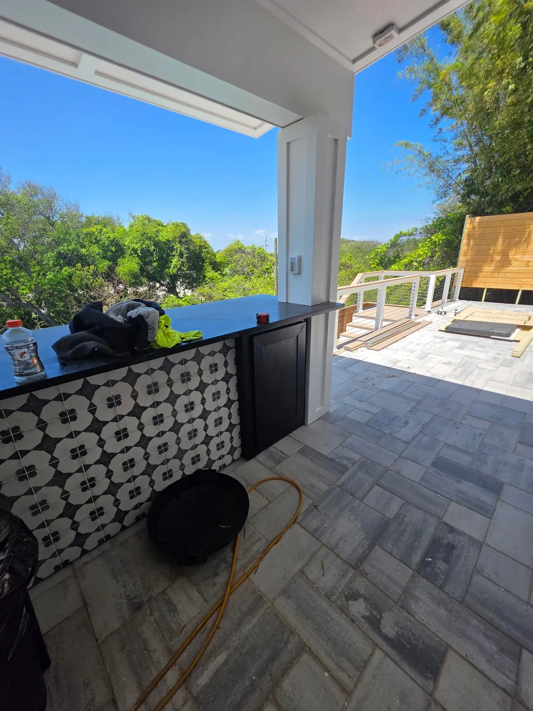 Outdoor bar during installation with patterned panels, dark cabinetry and a black countertop
