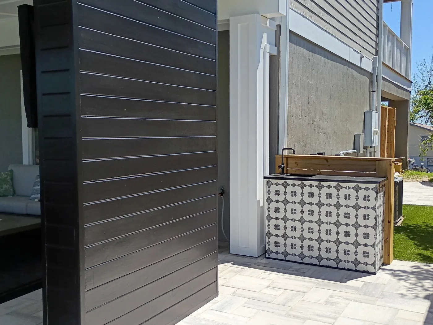 Cabana exterior with dark horizontal cladding, white trim and a patterned outdoor bar