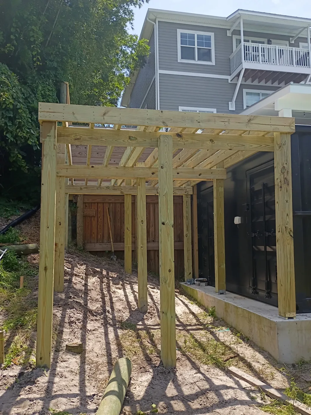 Wood deck posts and joists under construction beside the black container pool