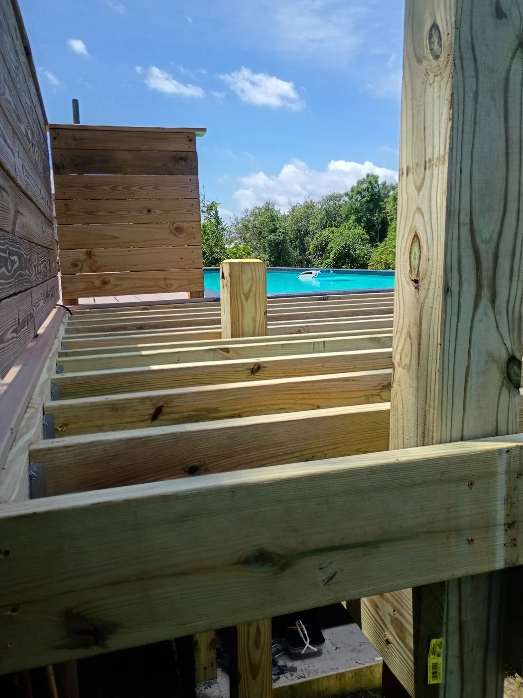 Open deck framing extending around a turquoise container pool