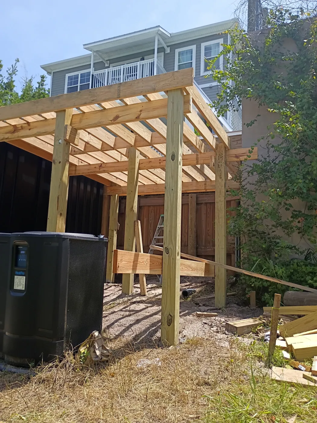 Raised wood deck framing with posts and joists beside the container pool