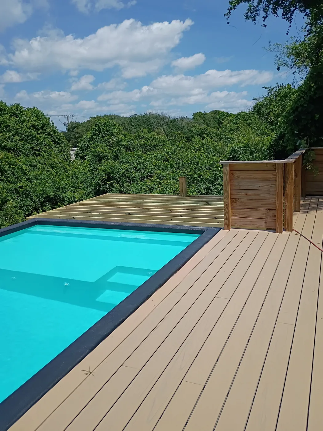 Deck boards in place around the container pool with unfinished framing still visible