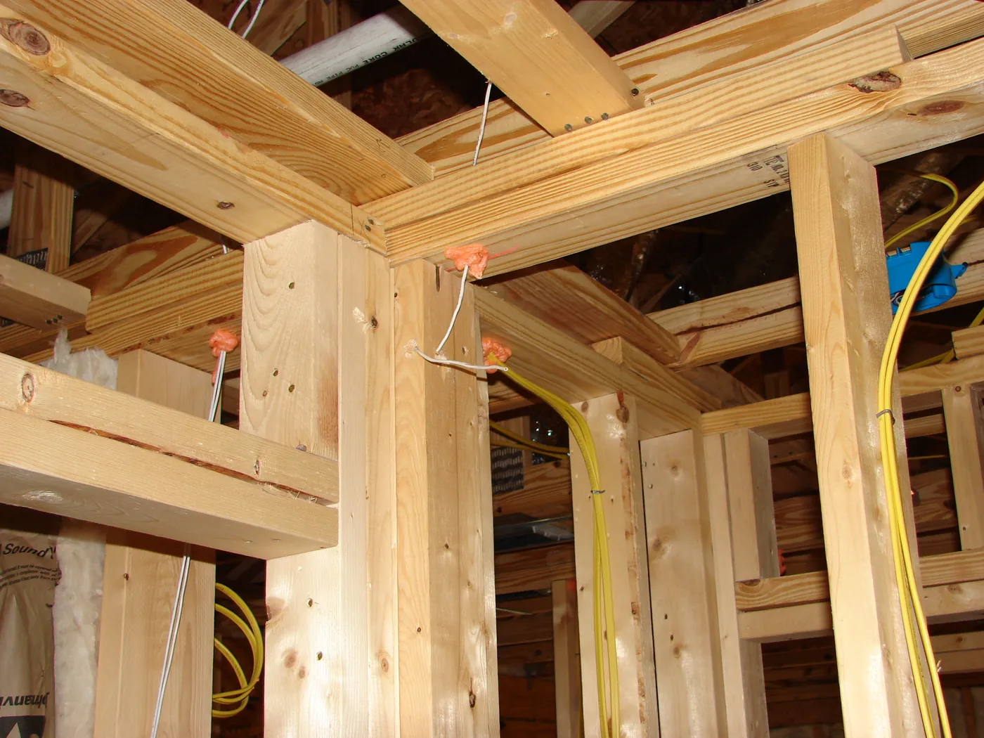 Yellow Romex electrical wiring run vertically through framed wall studs at rough-in stage