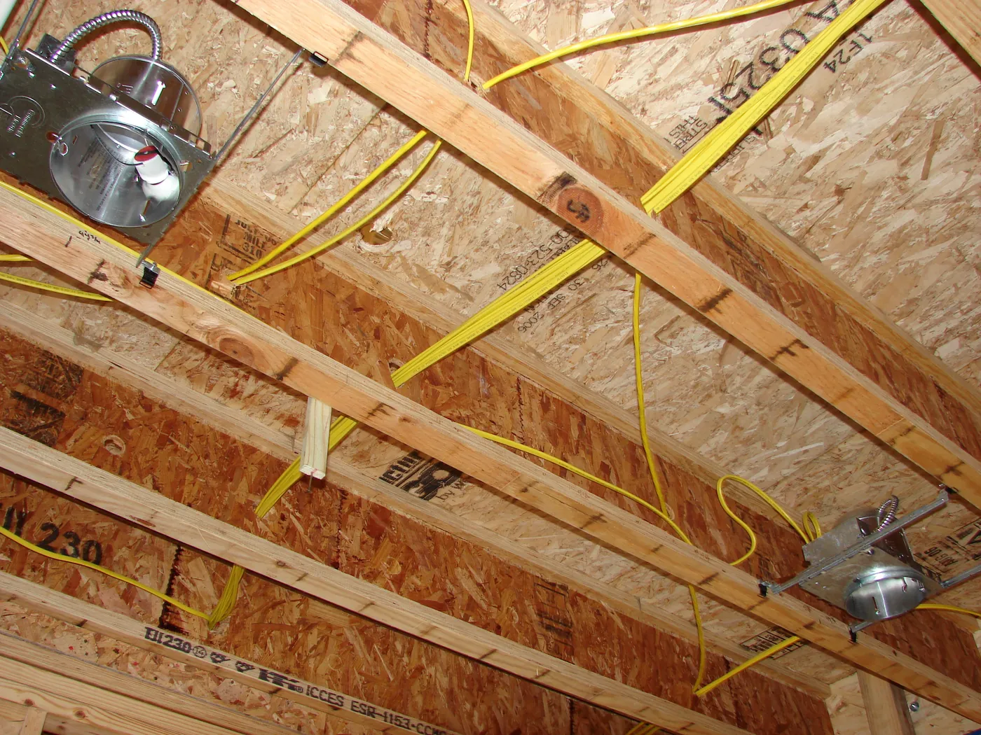 Romex electrical wiring stapled along floor joists in a framed structure