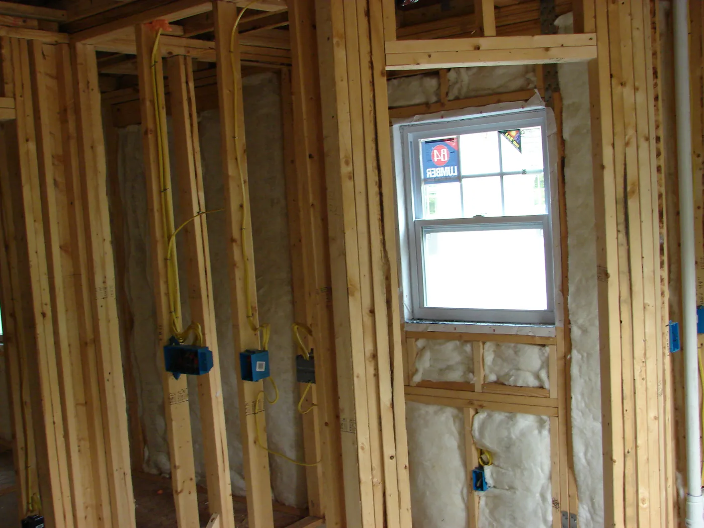 Electrical junction box wired to a wall stud below a window opening during rough-in