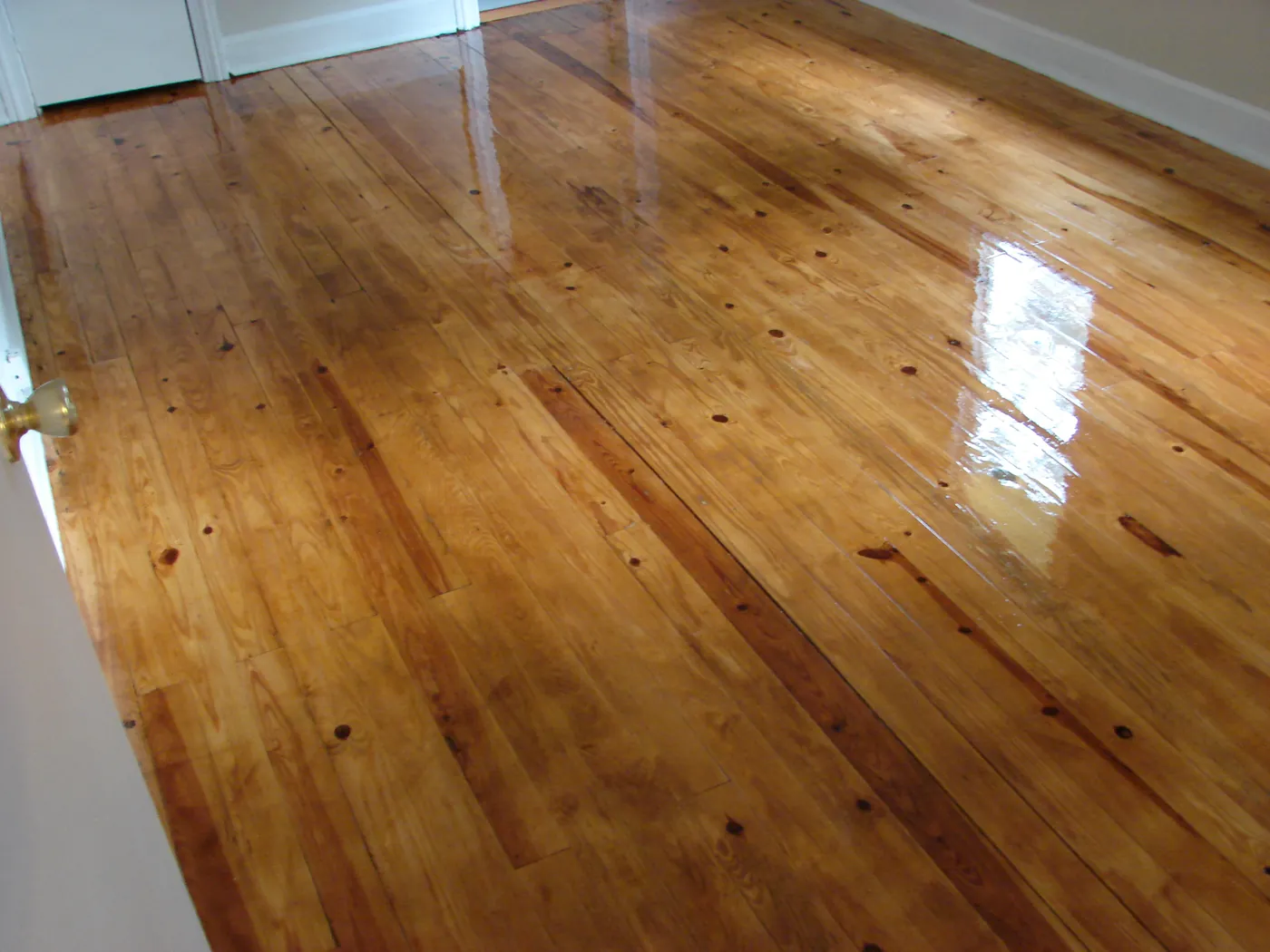 Restored heart pine floor with a smooth glossy topcoat catching window light