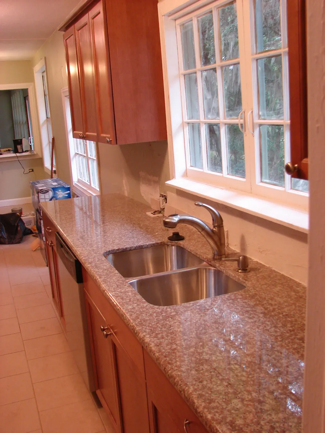 Kitchen with speckled granite countertop, undermount stainless sink, and cherry cabinets beneath a bright window