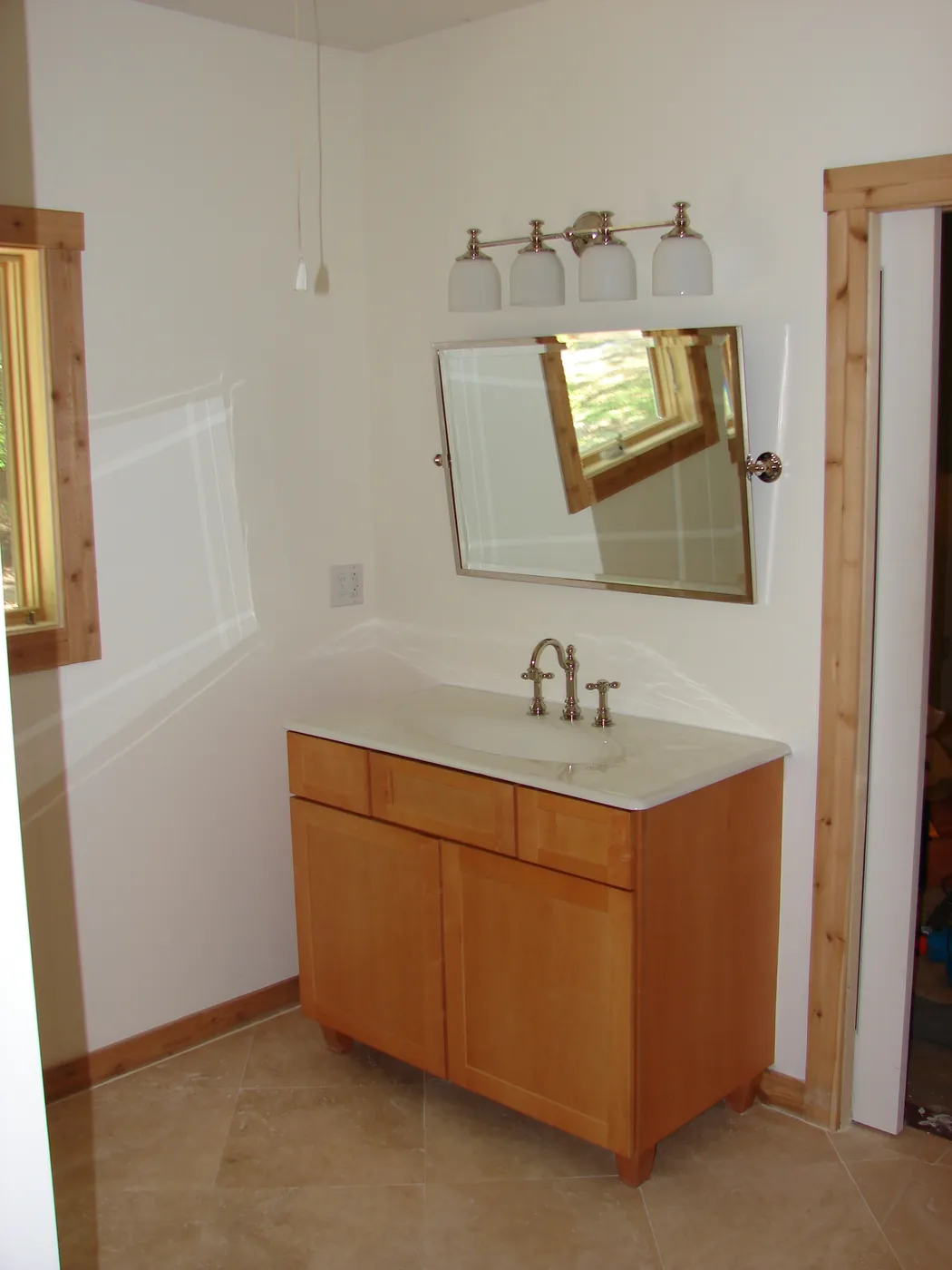 Bathroom vanity with wood cabinet, framed mirror and wall sconces in a clean finished powder room