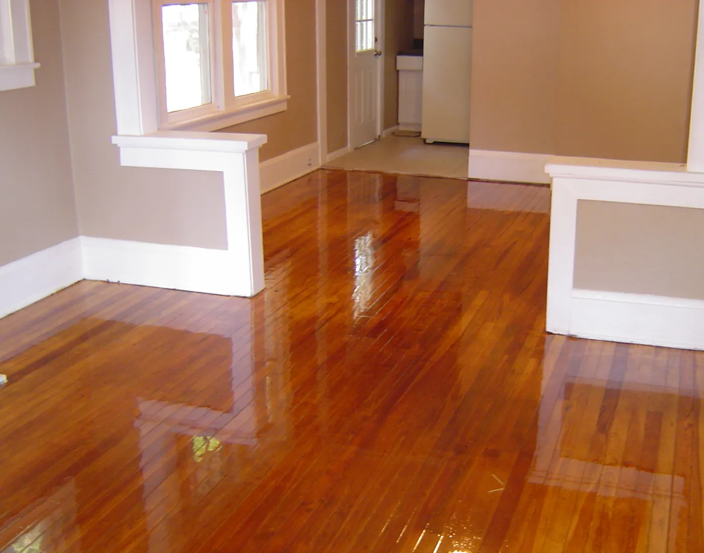 Warm tan painted walls with white window and door trim above a polished hardwood floor