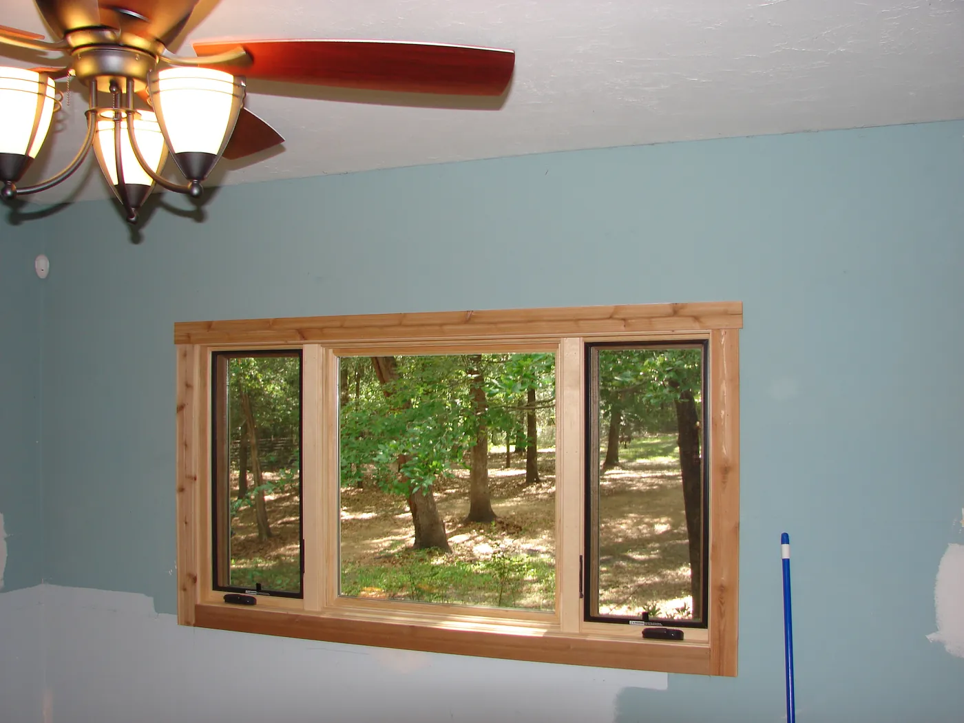 Interior wall painted a soft blue accent color framing wood-trimmed windows