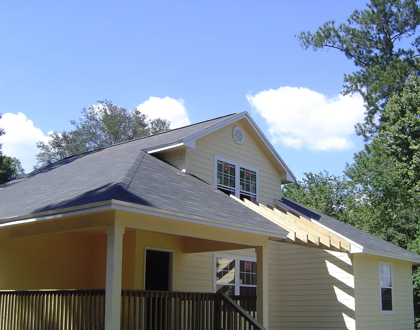 Exterior of a bungalow with freshly painted yellow siding and covered front porch