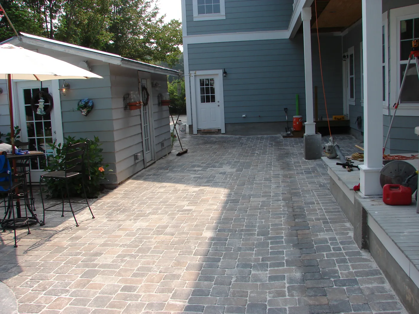 Herringbone-pattern paver walkway running along the side of a two-story home