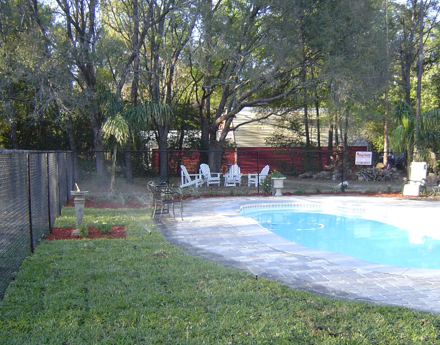 Backyard swimming pool bordered by a paver pool deck and coping