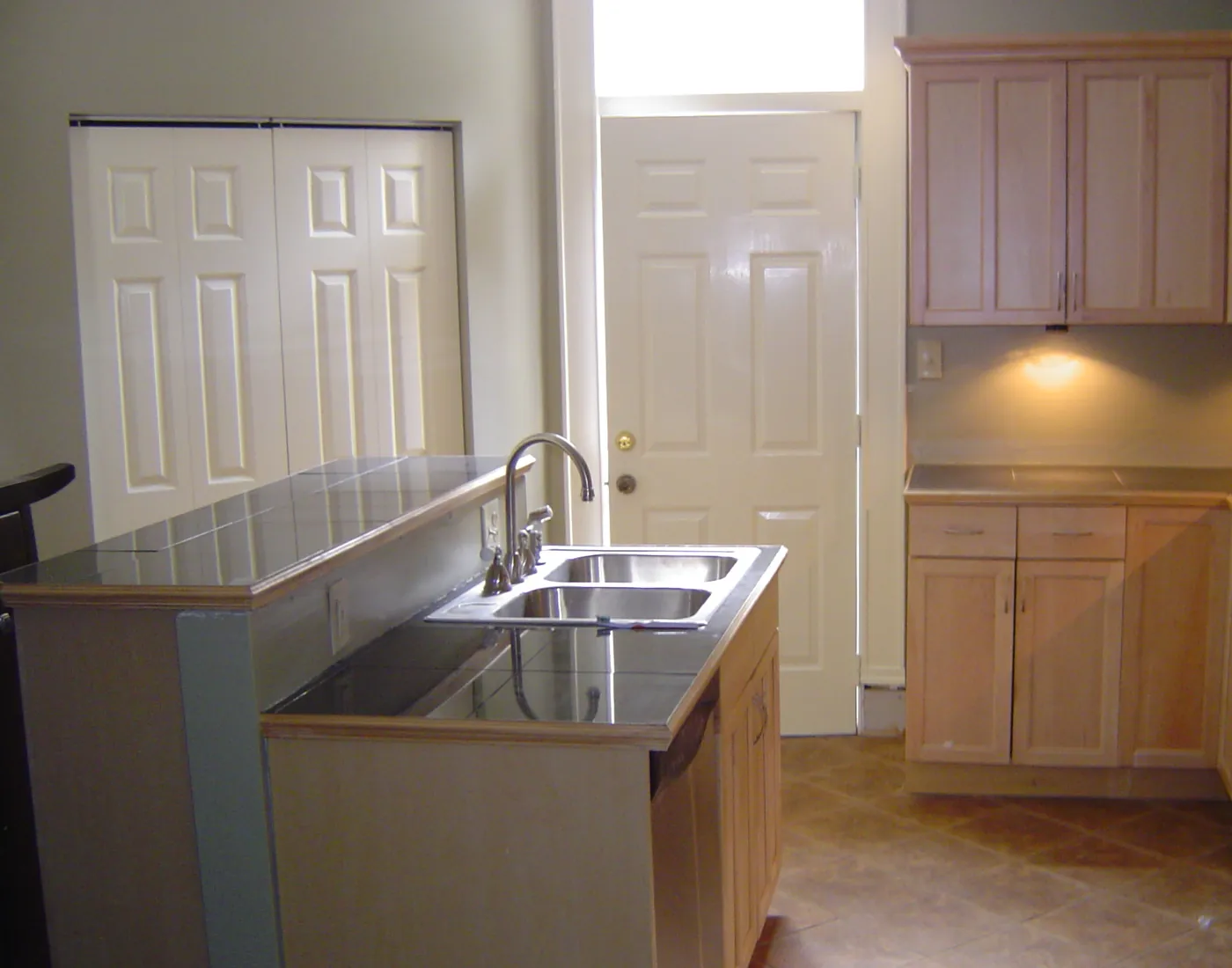 Stainless steel double-bowl sink plumbed into a maple cabinet run in a finished kitchen