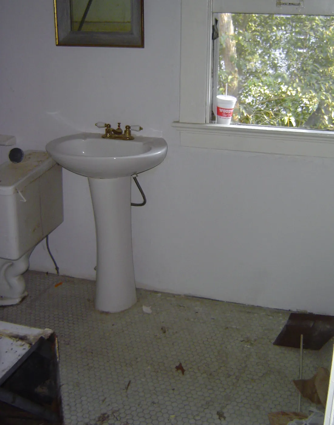 White pedestal sink and toilet installed in a bright bathroom with a window