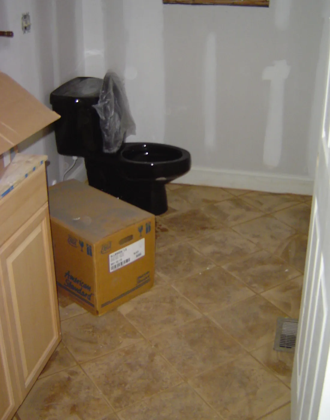 Newly installed black toilet in a freshly painted bathroom with tile floor