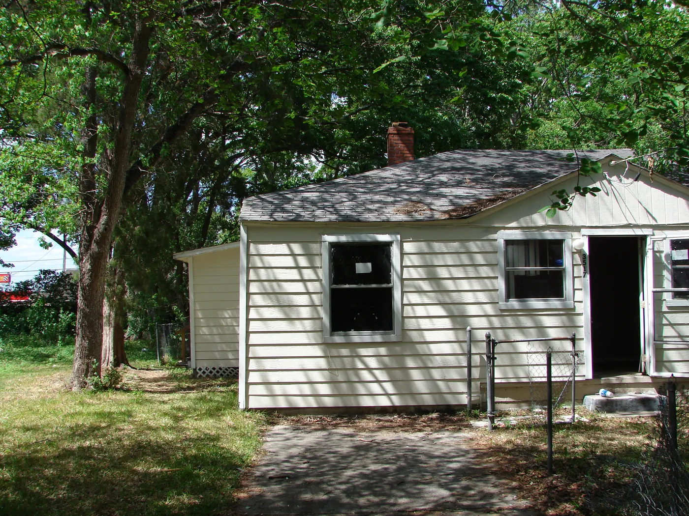 Front elevation of a single-story ranch home with freshly pressure-washed pale-green lap siding under shade trees