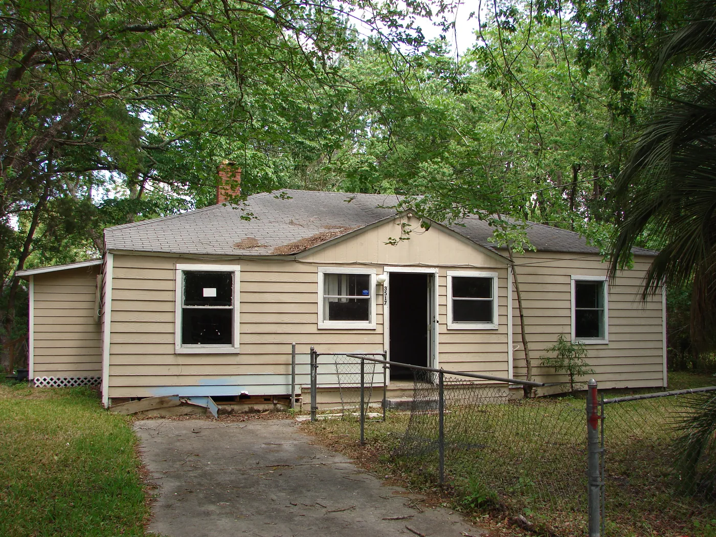 Full exterior view of a tan single-story home with clean, brightened siding and a tidy fenced front yard