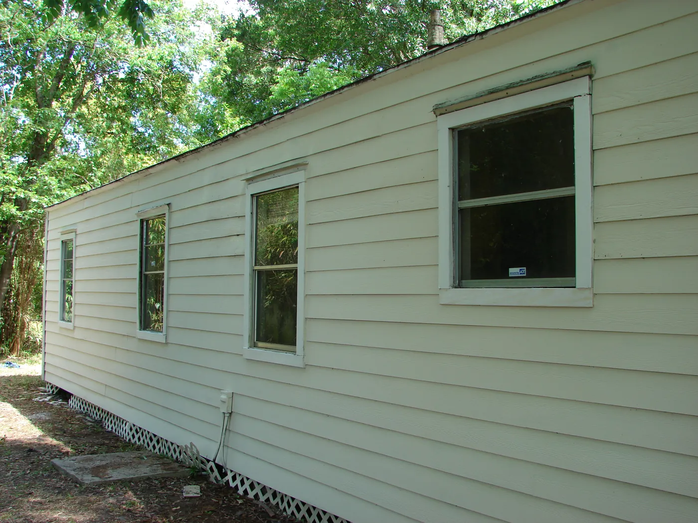 Long side wall of a home showing clean, uniform pale-green horizontal lap siding after pressure washing