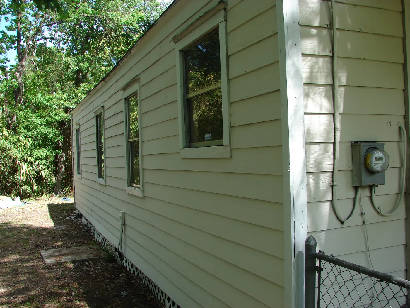 Rear elevation of a home with cleaned light-green siding and a mounted electric meter, exterior restored