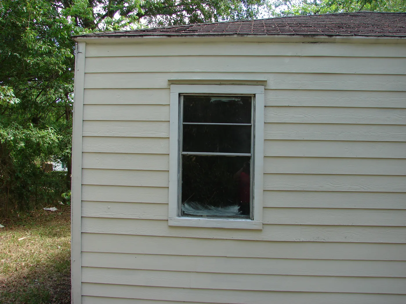 Corner of a home with a single window showing bright, pressure-washed light-green siding