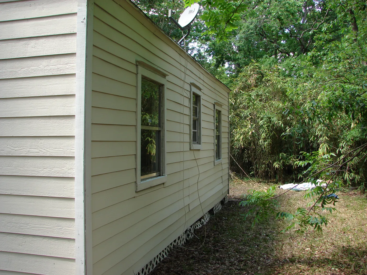 East side wall of a home with clean pale siding after pressure washing, well lit in daylight