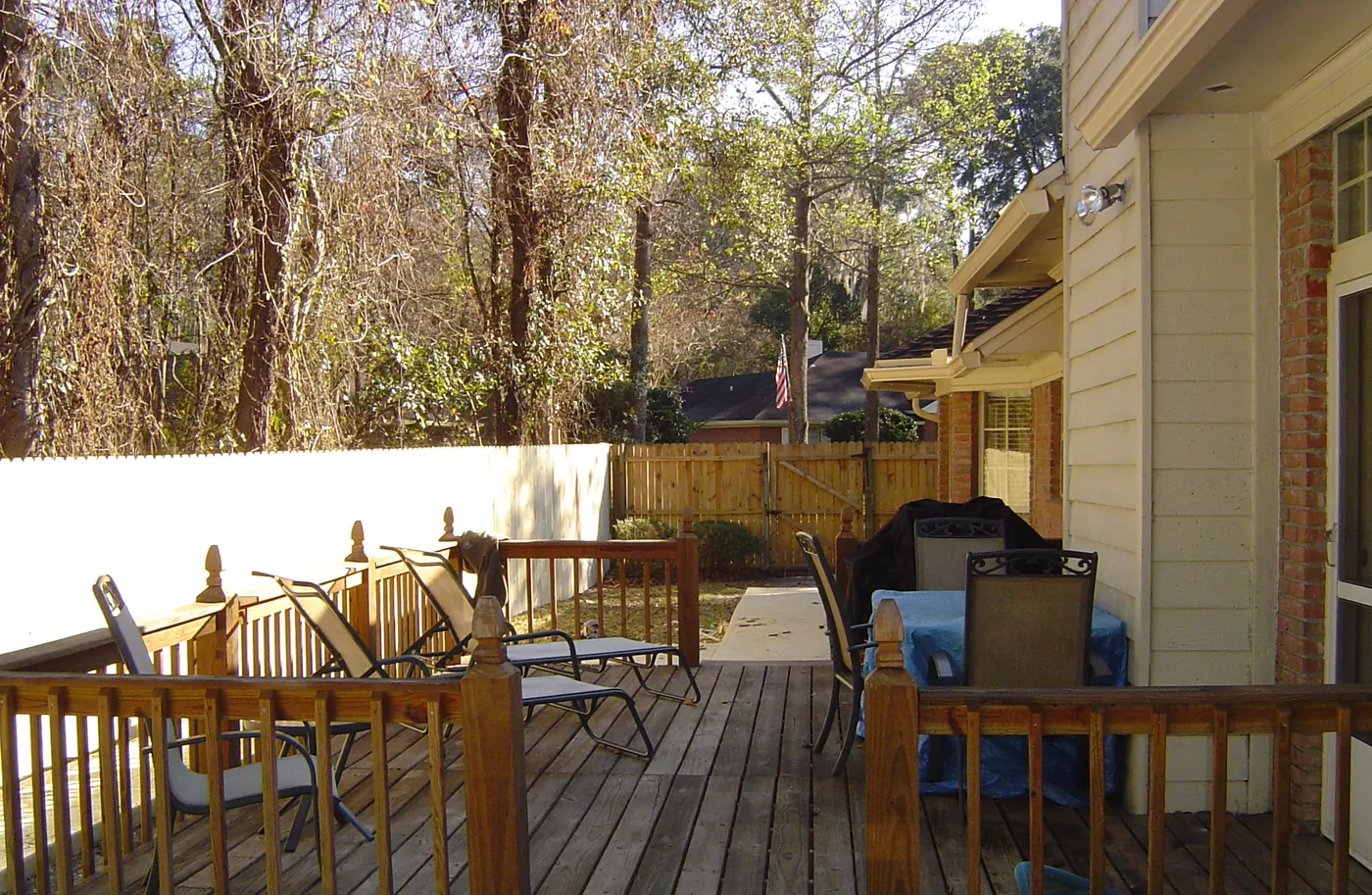 Cleaned wood-plank backyard deck with patio furniture behind a home