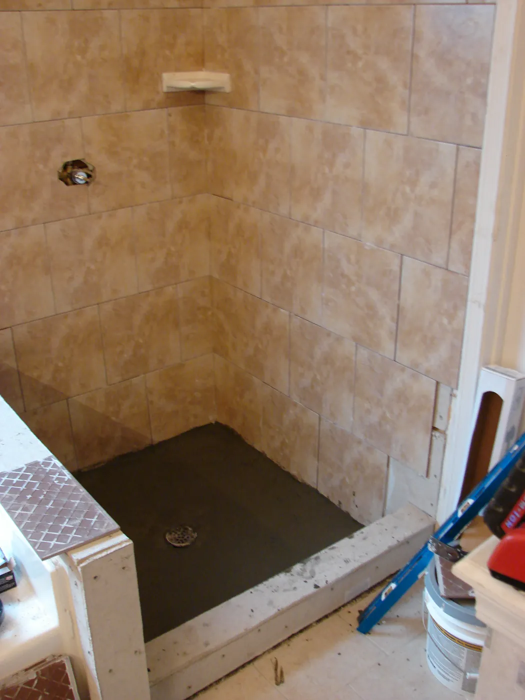 Finished walk-in shower with beige porcelain tile walls and mosaic accent band