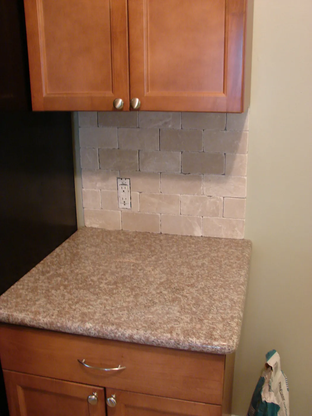 Tumbled travertine stone backsplash above a stone countertop in a kitchen