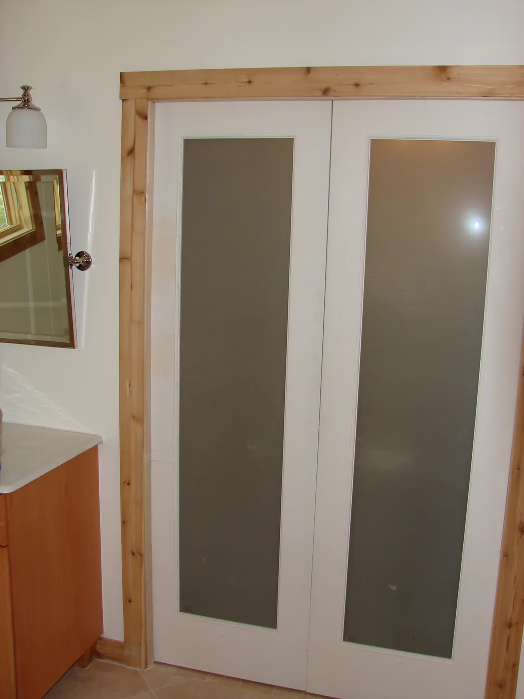 Frosted-glass French doors hung in a natural wood frame with matching window casing