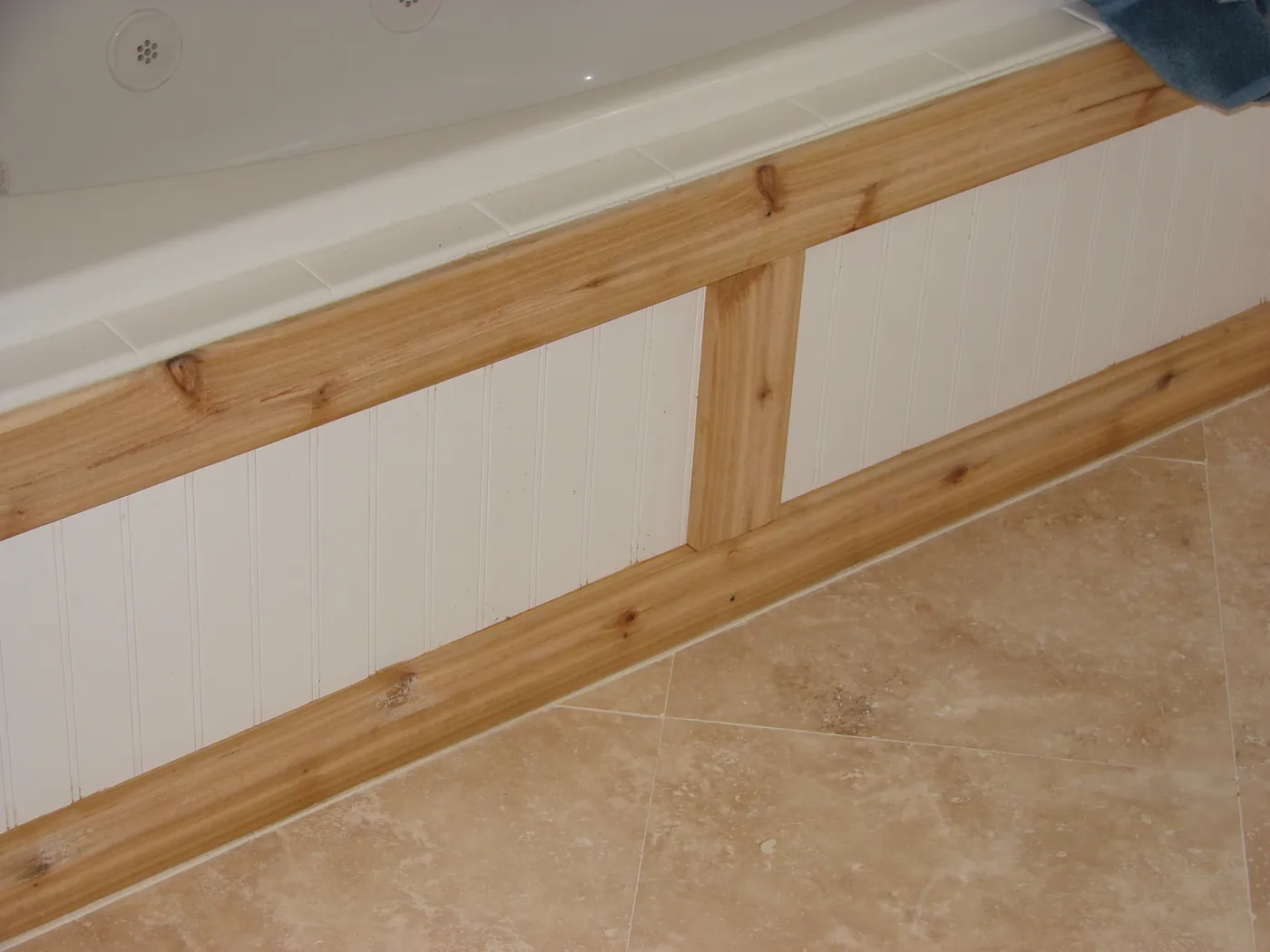 Beadboard wainscoting capped with a wood chair rail above a travertine tile floor