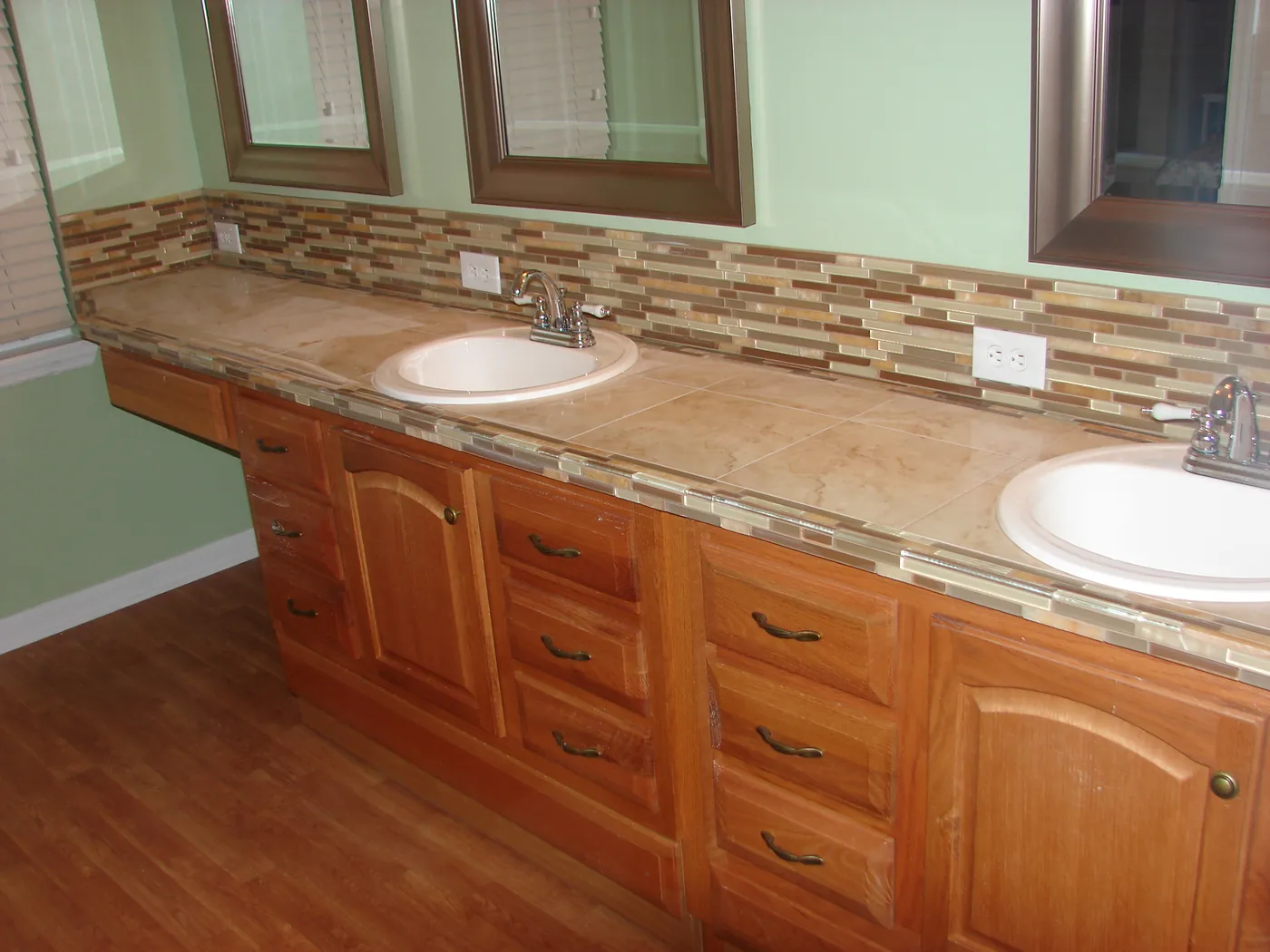 Double bathroom vanity with raised-panel wood cabinets and wood-framed mirrors above a tile backsplash
