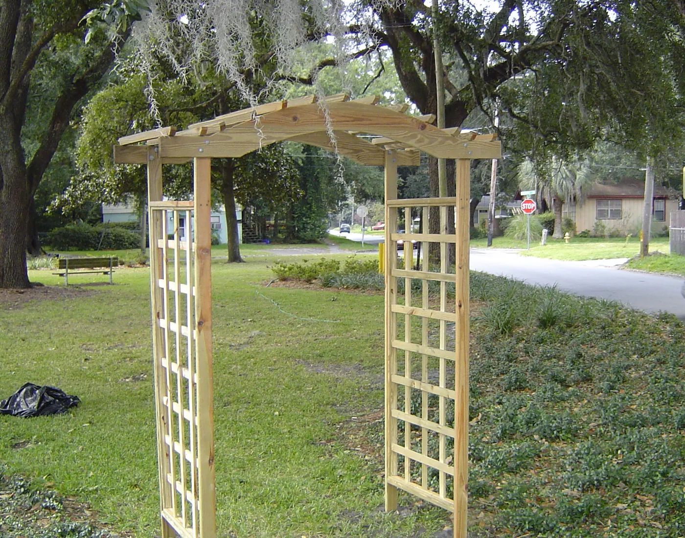 Handcrafted wood garden arbor with lattice sides set on a front lawn