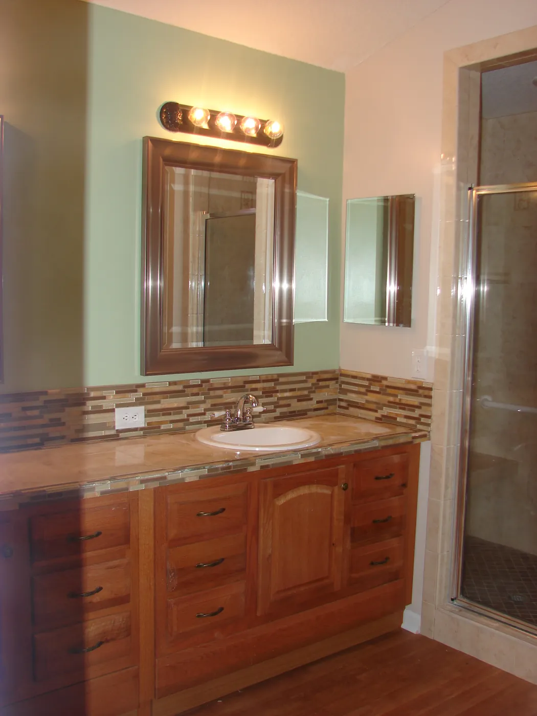 Bathroom wood vanity cabinet with a wood-framed mirror and mosaic tile backsplash